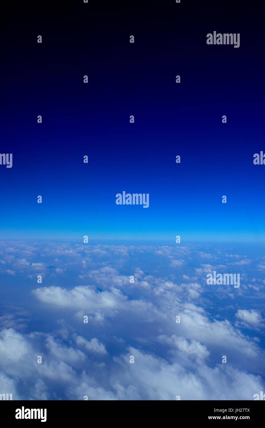 Bella vista delle nuvole sotto e il profondo blu del cielo sopra come si vede dal finestrino per aerei Foto Stock