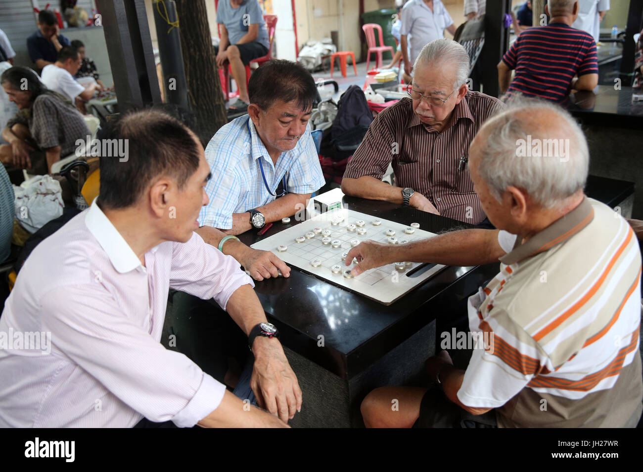 Gruppi di persone si radunano per la riproduzione di bozze e altri giochi da tavolo per le strade di Chinatown. Singapore. Foto Stock