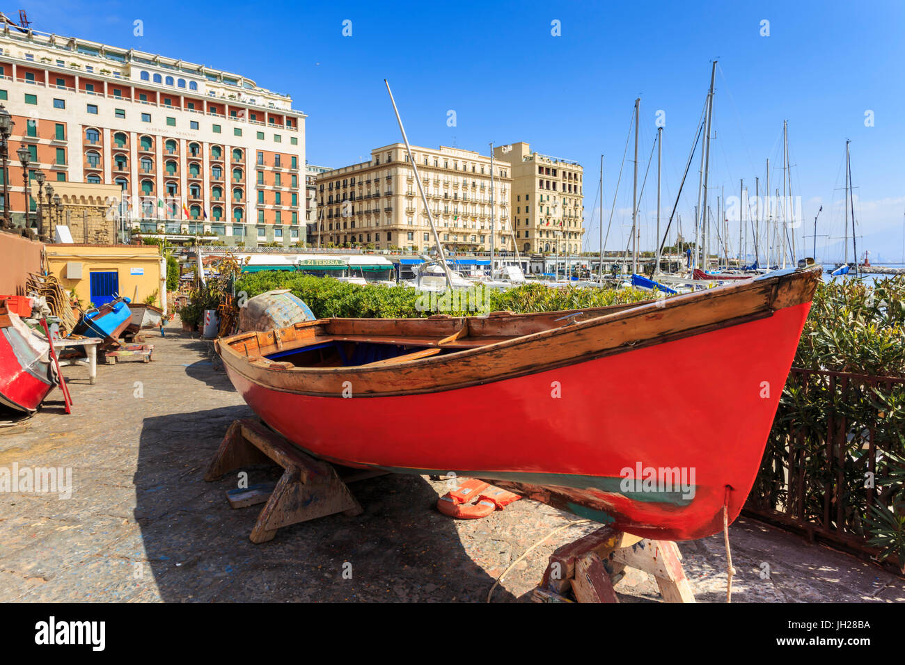 Colorate barche a remi in riparazione presso la marina Borgo Marinaro, con sfondo di Grand Hotel Chiaia, città di Napoli, Italia Foto Stock