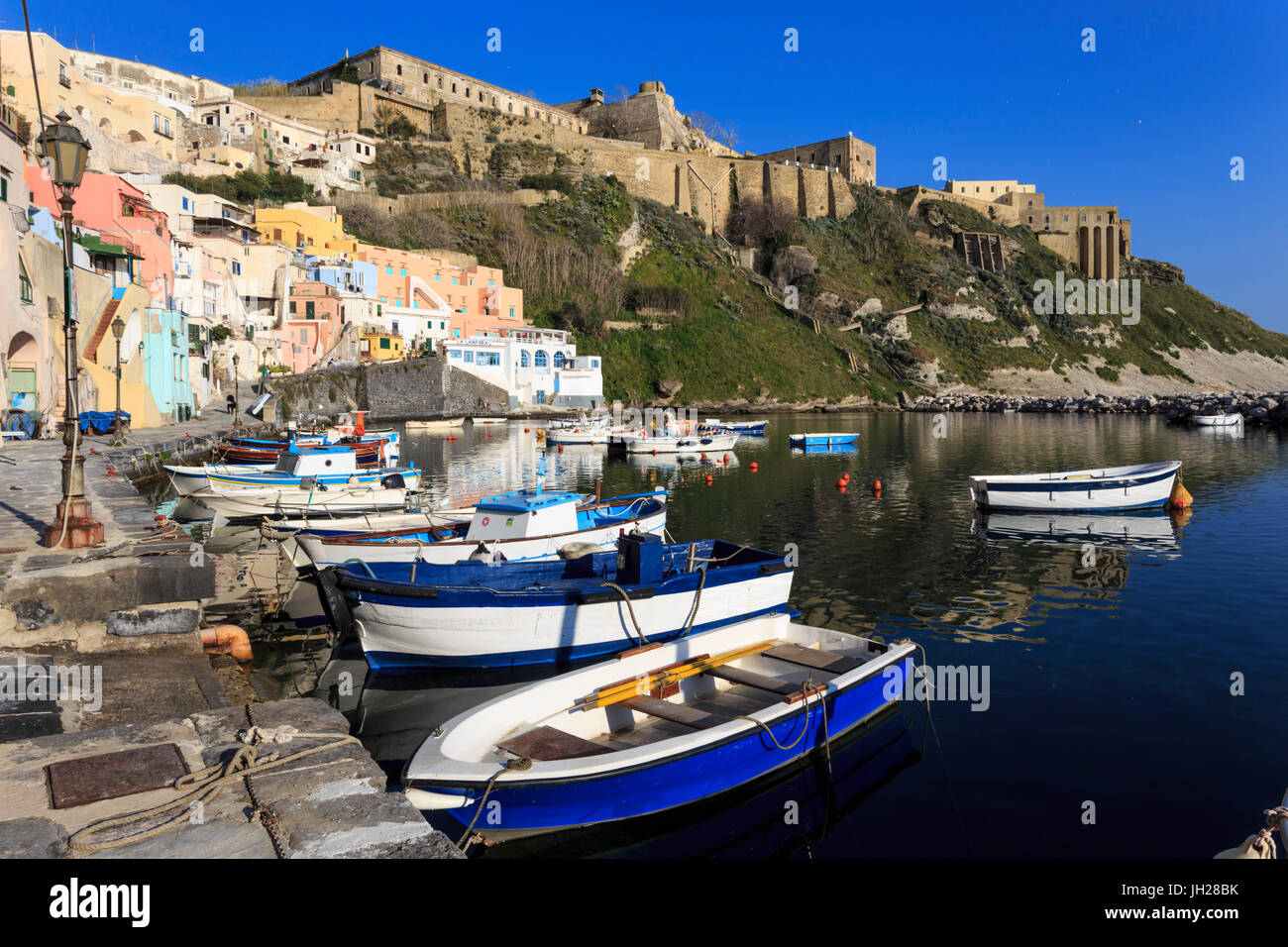 Marina Corricella, grazioso villaggio di pescatori, barche sotto Terra Murata acropoli fortezza, Isola di Procida e della baia di Napoli, Italia Foto Stock