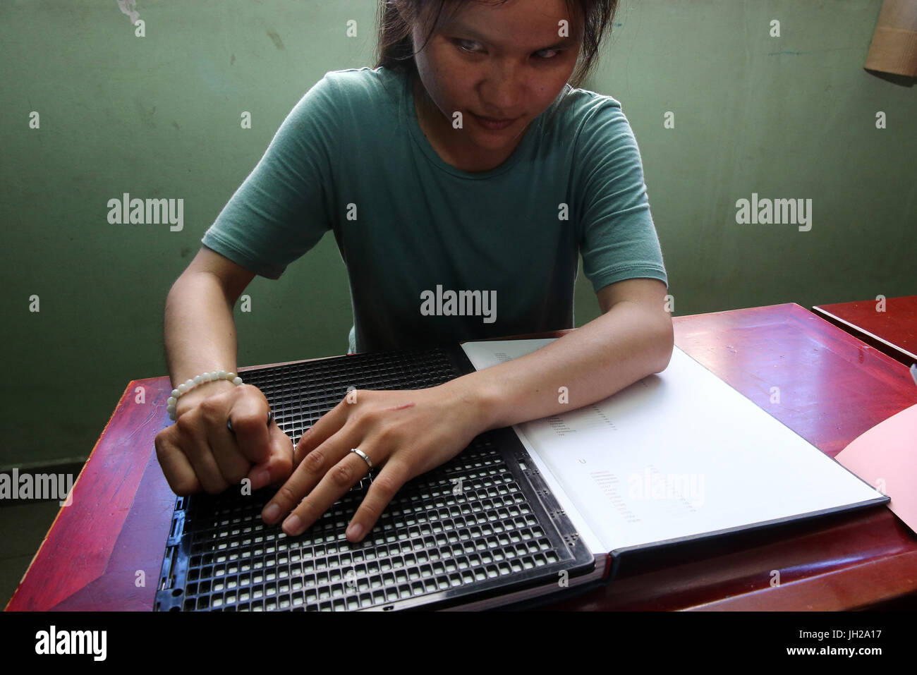 Il Vietnam. Centro per i bambini ciechi. Ragazza scrittura braille. Foto Stock