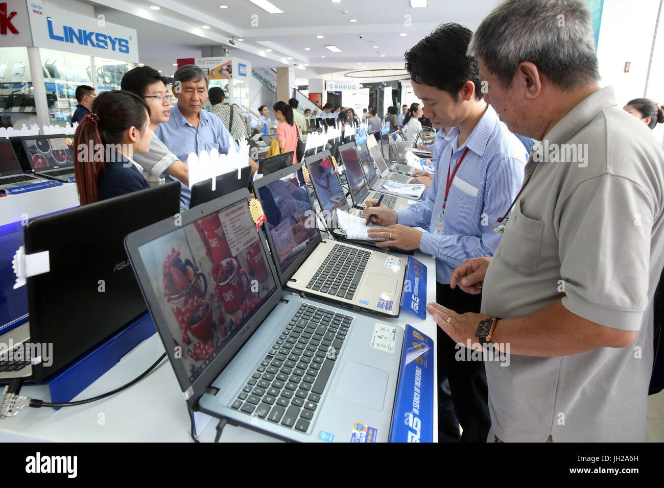 Negozio di elettronica. Shop Assistant aiutando un cliente con un computer portatile. Ho Chi Minh City. Il Vietnam. Foto Stock