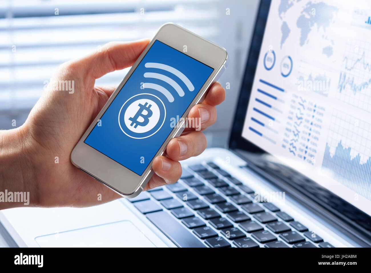 Persona che invia bitcoin con lo smartphone per il pagamento on-line, primo piano dello schermo di cellulare, business office background Foto Stock