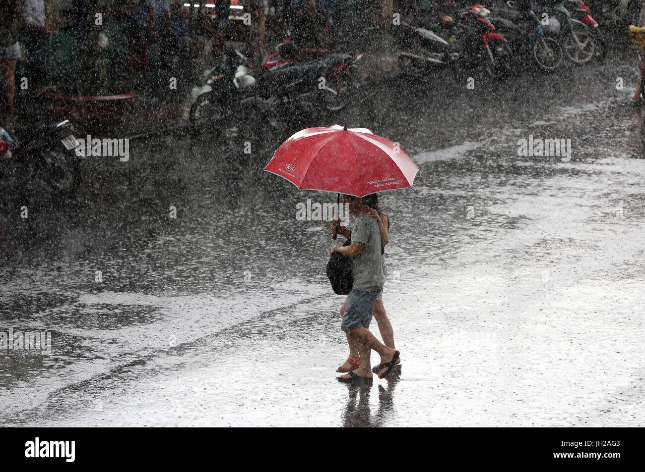 Forti piogge monsoniche. Giovane con ombrellone sulla strada di Saigon. Il Vietnam. Foto Stock
