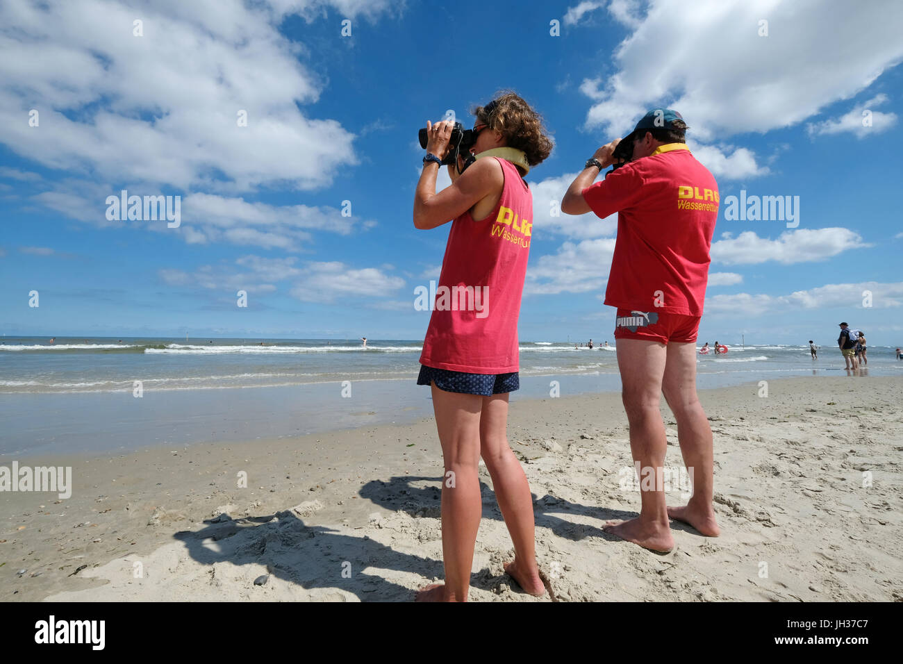 Membri della DLRG vita tedesca il salvataggio della società guarda il nuotatore in onde del mare del Nord sulla spiaggia dell'isola di Spiekeroog, Germania Foto Stock