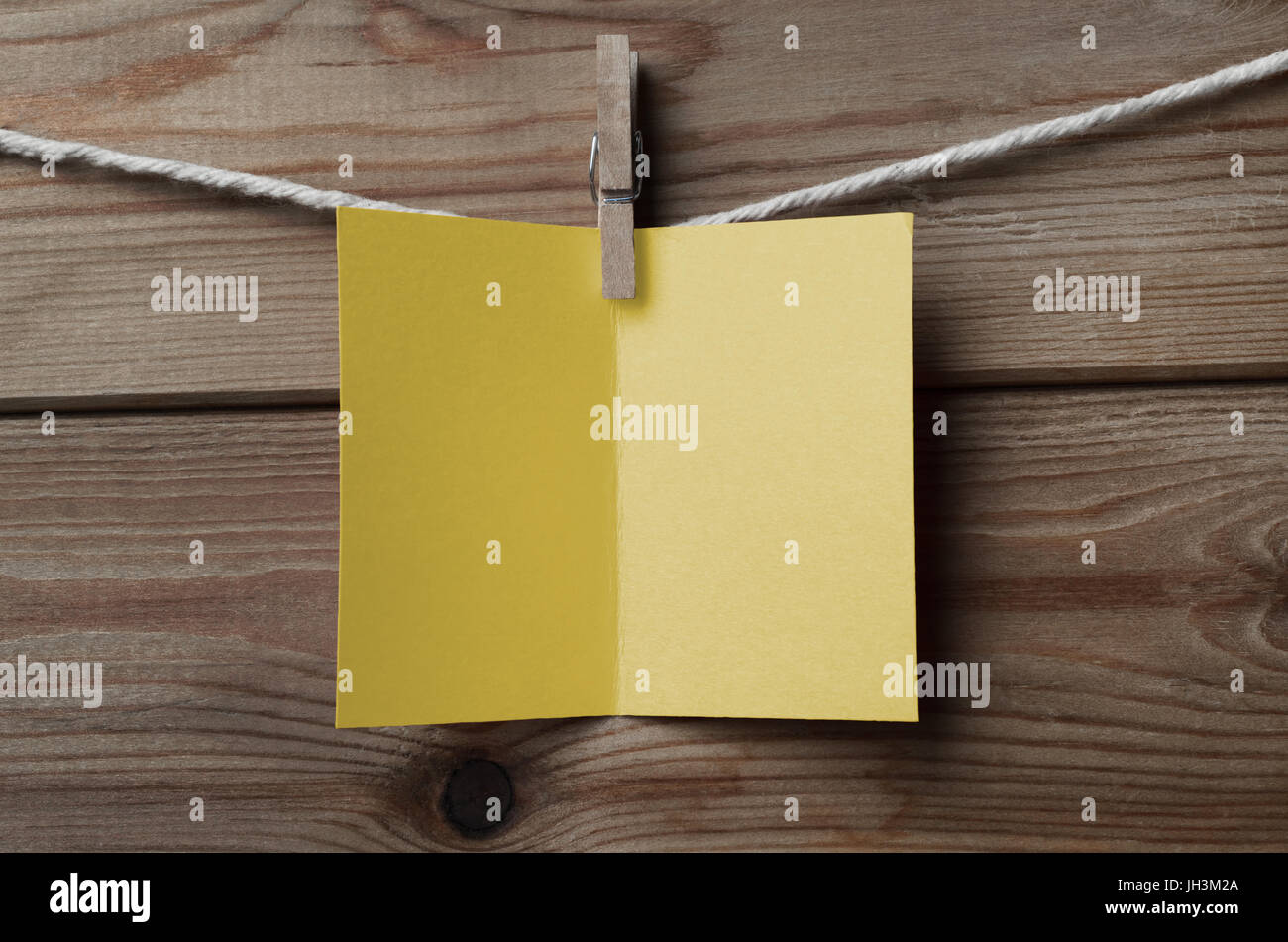 Un aperto, giallo vuota della scheda Messaggi di saluto, ancorato alla stringa contro asse di legno sfondo Foto Stock