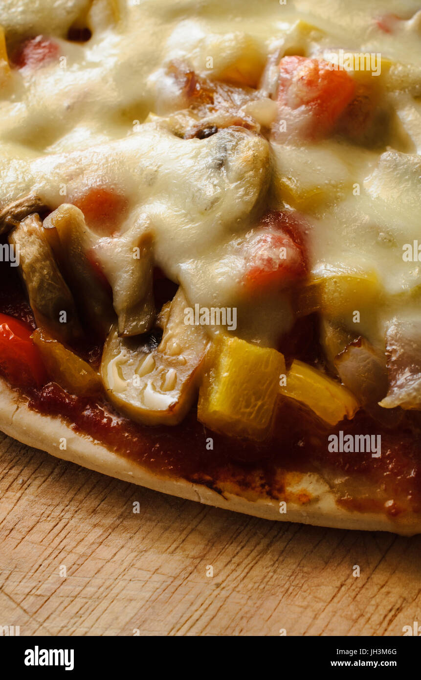 Close up (macro) di un cotto pizza vegetariana, con peperoni rossi e gialli, cipolle, funghi e mozzarella, su graffiato in legno cinghiale di trinciatura Foto Stock