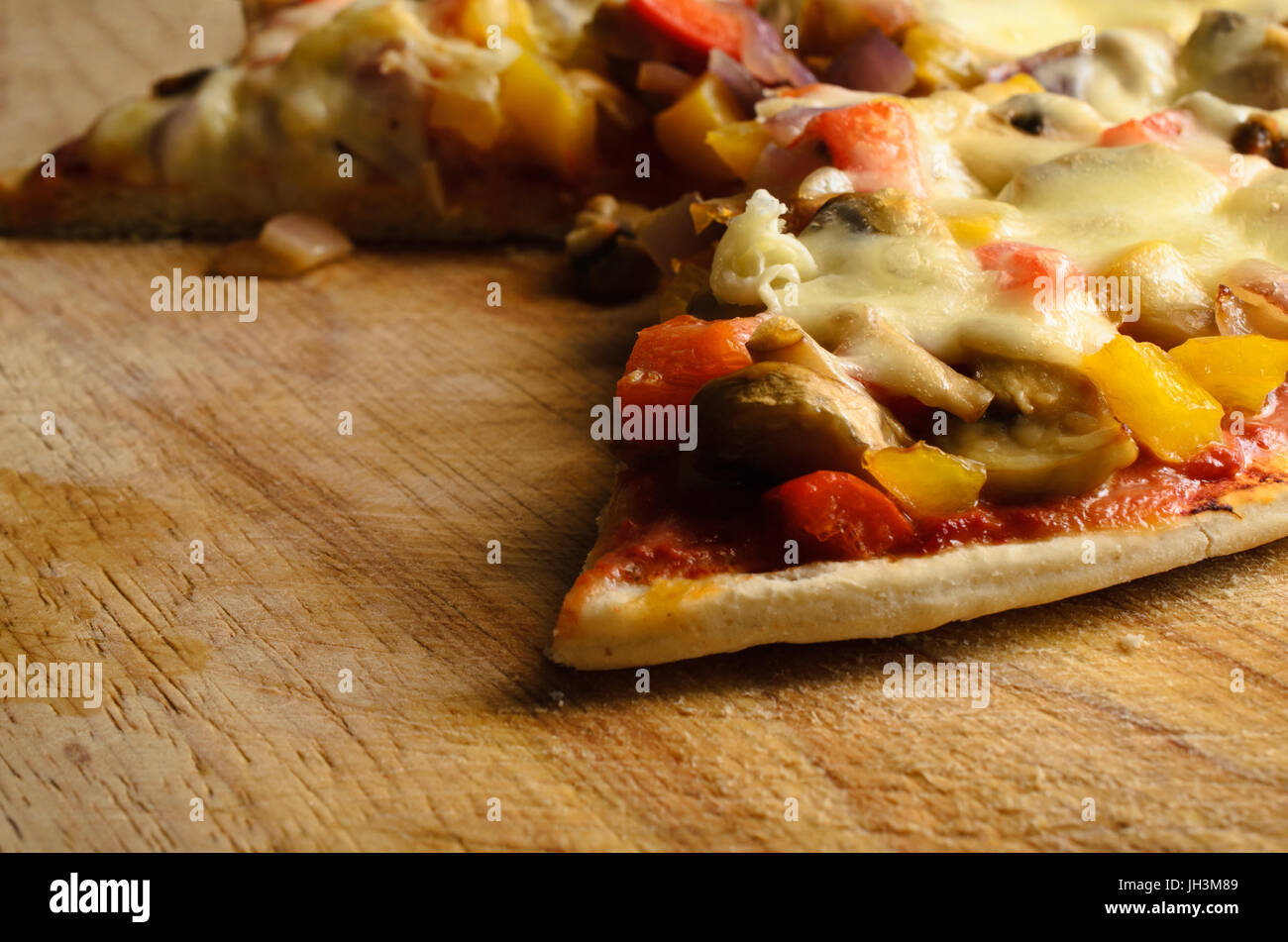 Cucinato e servito e in parte mangiato pizza vegetariana su tavola di legno con fette rimosso Foto Stock