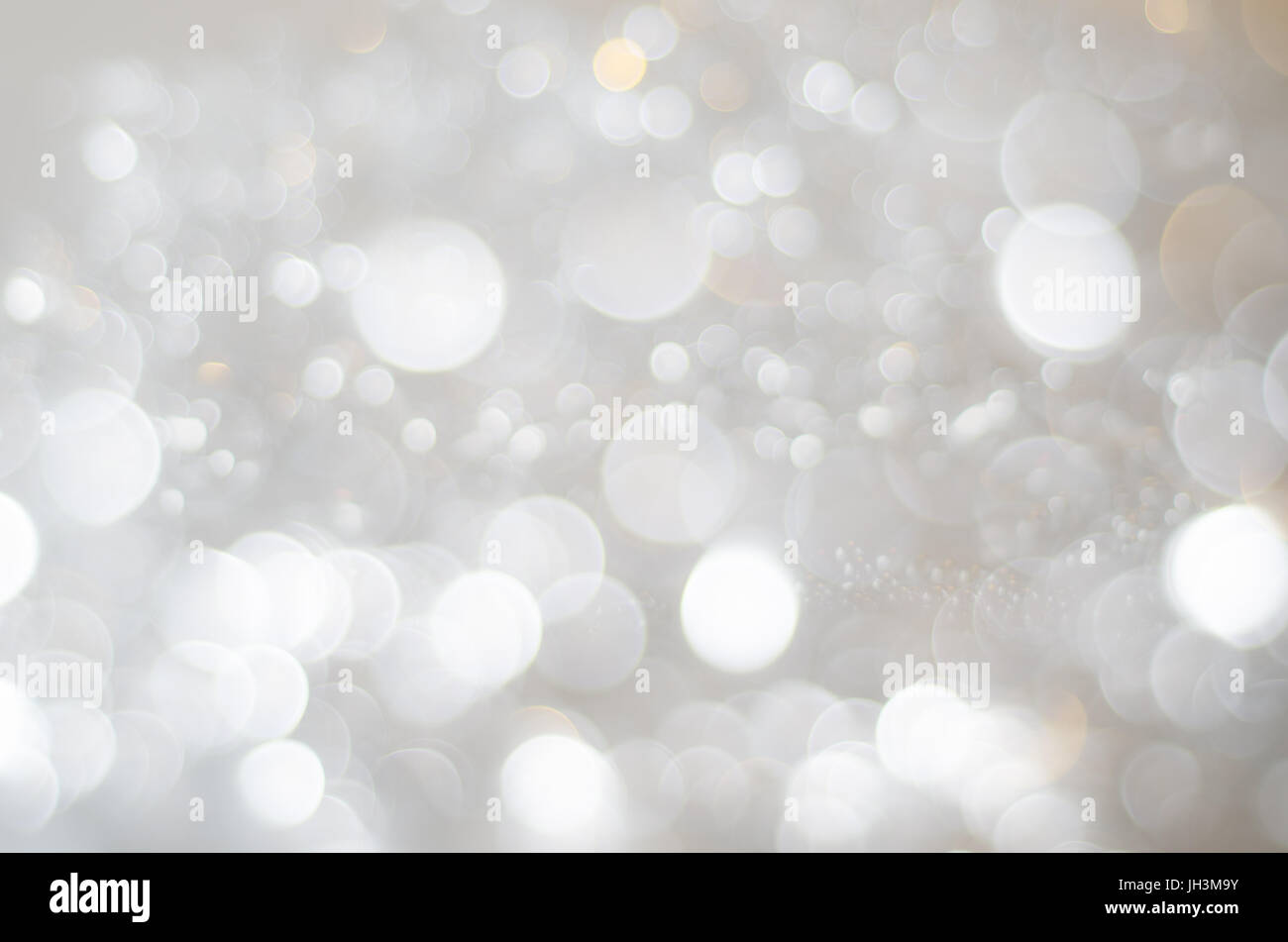 Un bokeh texture di sfondo grandi e piccoli cerchi in bianco, grigio argento e rame morbido oro. Foto Stock