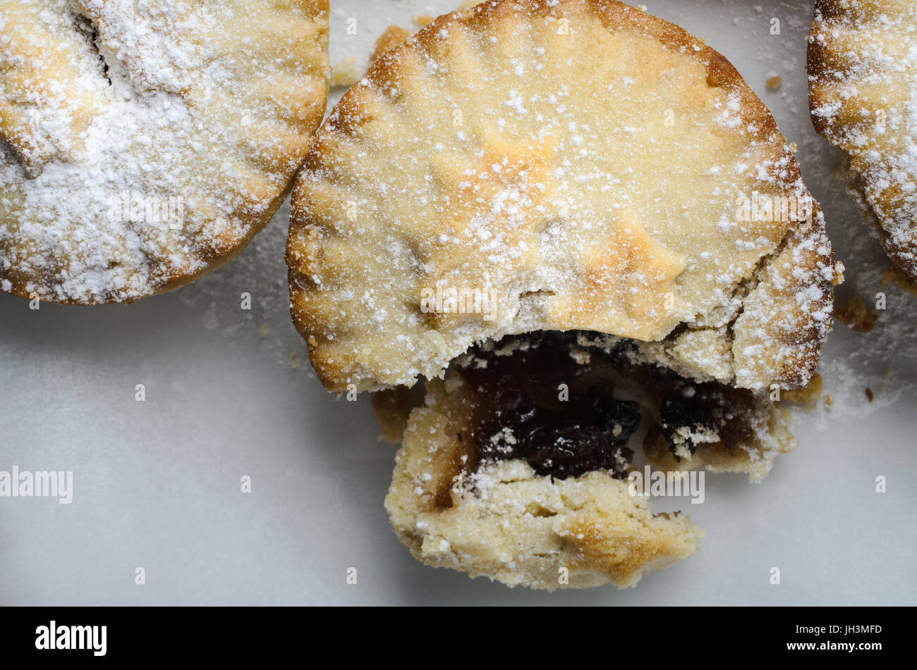 In prossimità di uno dei tre Natale pasticci di carne macinata, rottura aperta per esporre il riempimento, con sbriciolare la pasticceria. Foto Stock