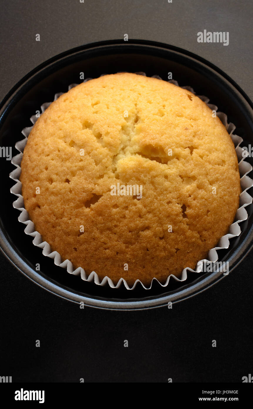 Tettuccio di close up di una sola tazza torta nel caso della carta, nella rientranza del black bun stagno. Foto Stock