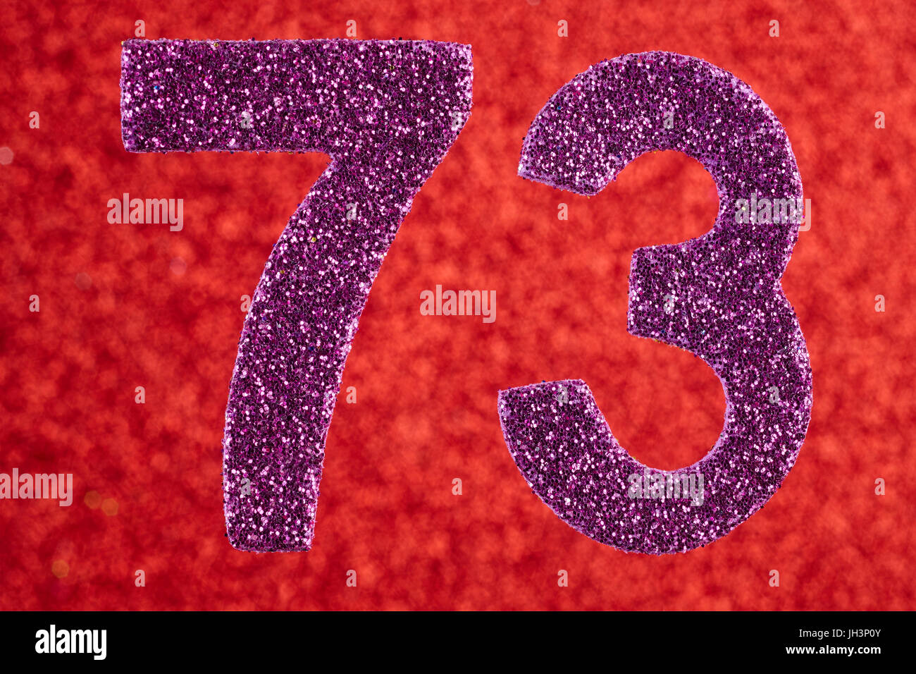 Numero settanta-tre color porpora su uno sfondo rosso. Anniversario. Posizione orizzontale Foto Stock
