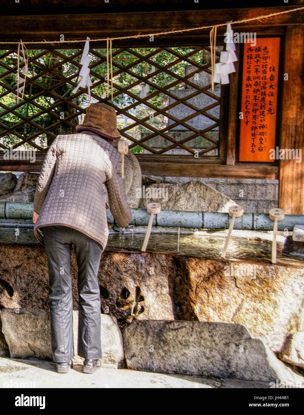 Una donna con bacino di depurazione, te-mizuya, al Santuario Sumiyoshi. Osaka, Giappone Foto Stock