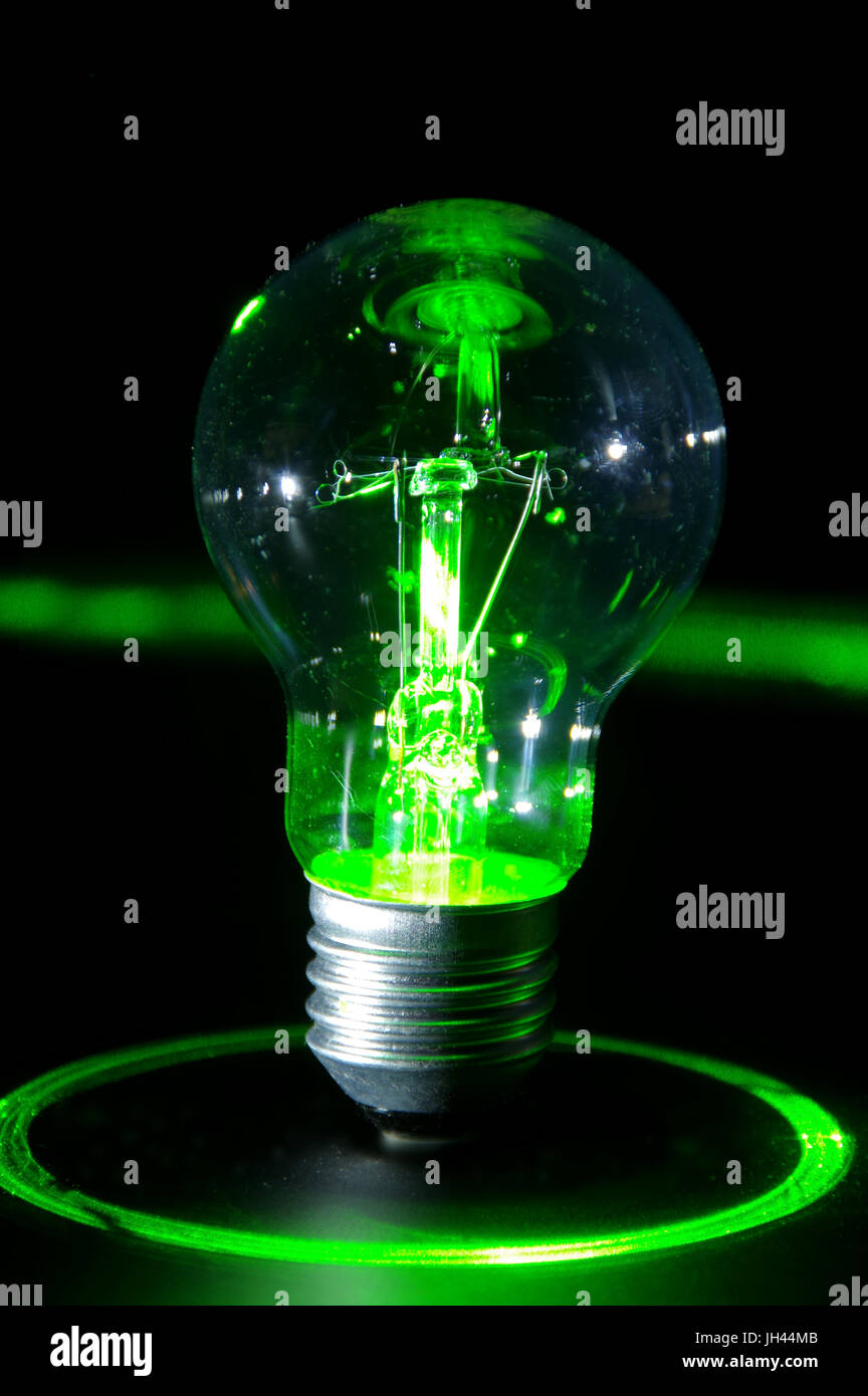 Concetto classico di lampadina spia di alimentazione verde con raggi laser. Foto Stock