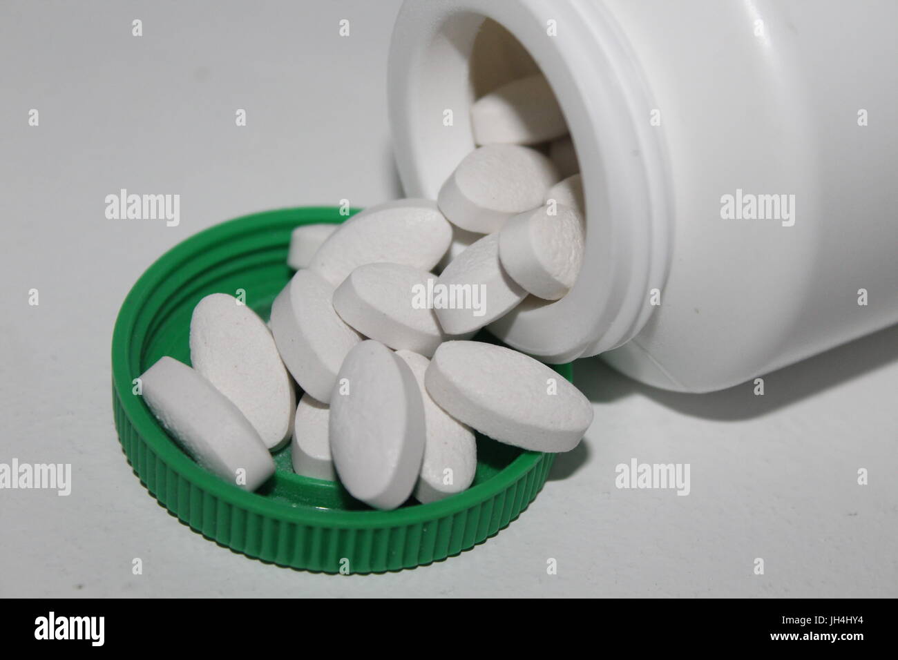 Pillole di bianco fuoriuscita dalla bottiglia Foto Stock
