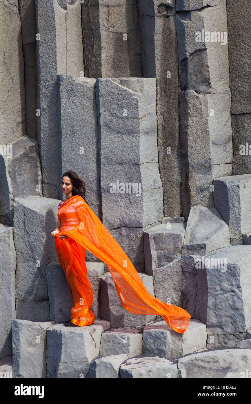 Donna indiana in posa sulle colonne di basalto in spiaggia Reynisfjara in Islanda Foto Stock