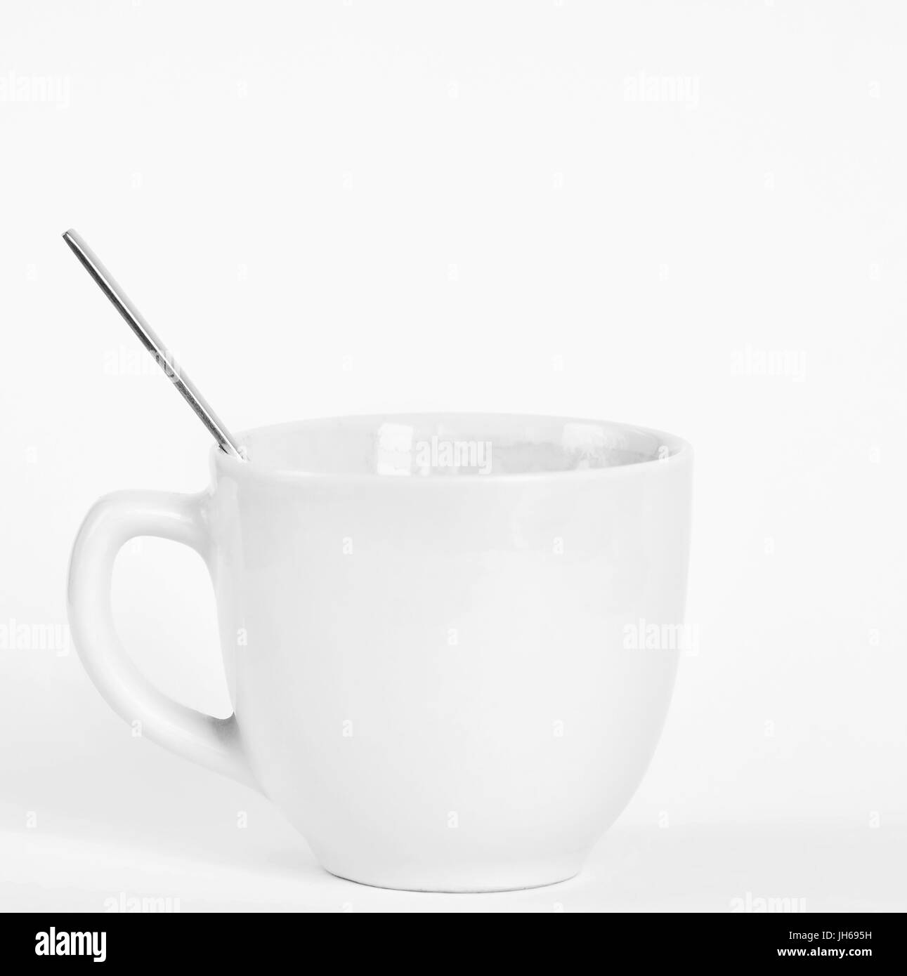Un piccolo white tazza di caffè con un cucchiaio. Isolato su un pulito sullo sfondo bianco. Foto Stock