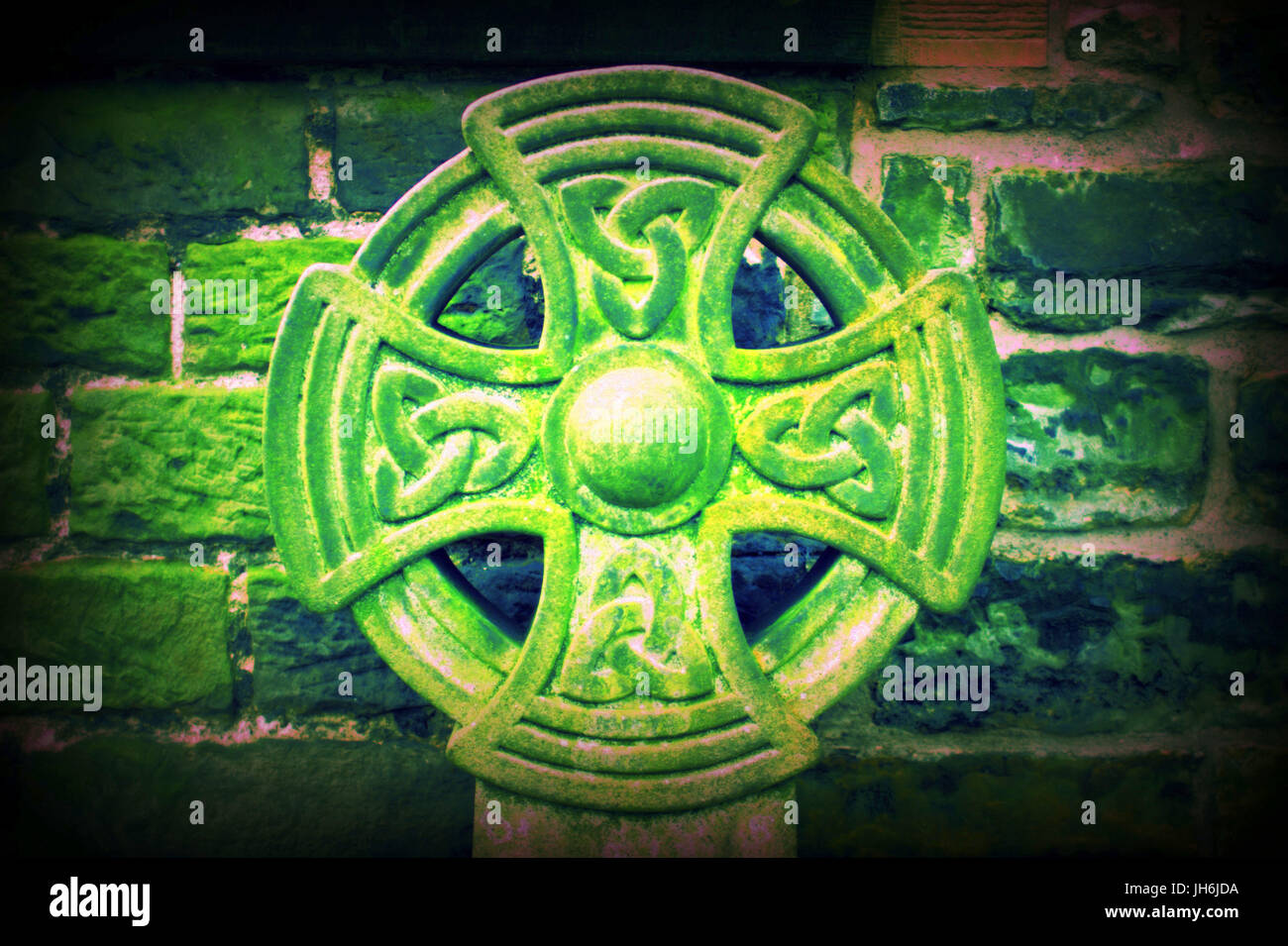 Green Cross celtica contro il muro di pietra Foto Stock