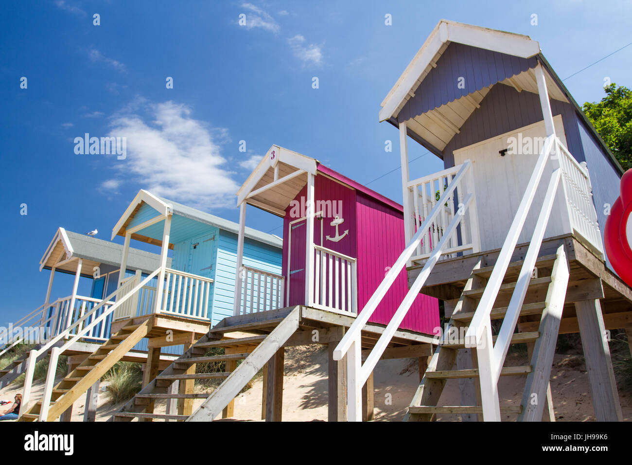 Righe della pittoresca spiaggia di capanne su palafitte sulla soleggiata spiaggia di sabbia a Wells accanto al mare in Norfolk, Regno Unito che è una meta turistica molto beach in Inghilterra. Foto Stock