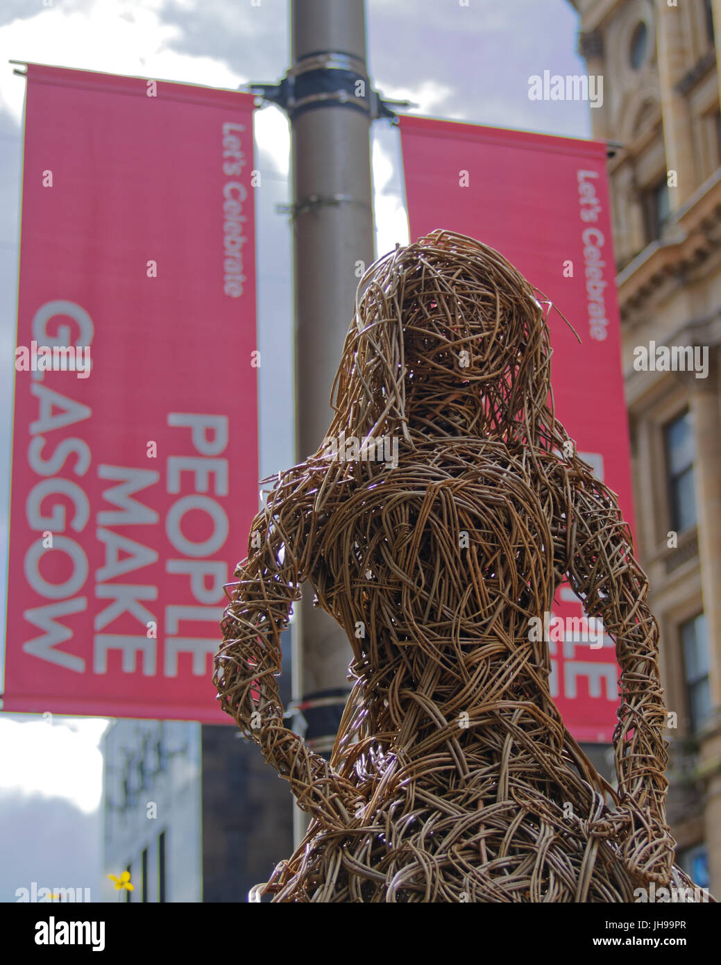 Le persone fanno Glasgow banner accanto a basket weave donna artwork statua a Buchanan Street Foto Stock