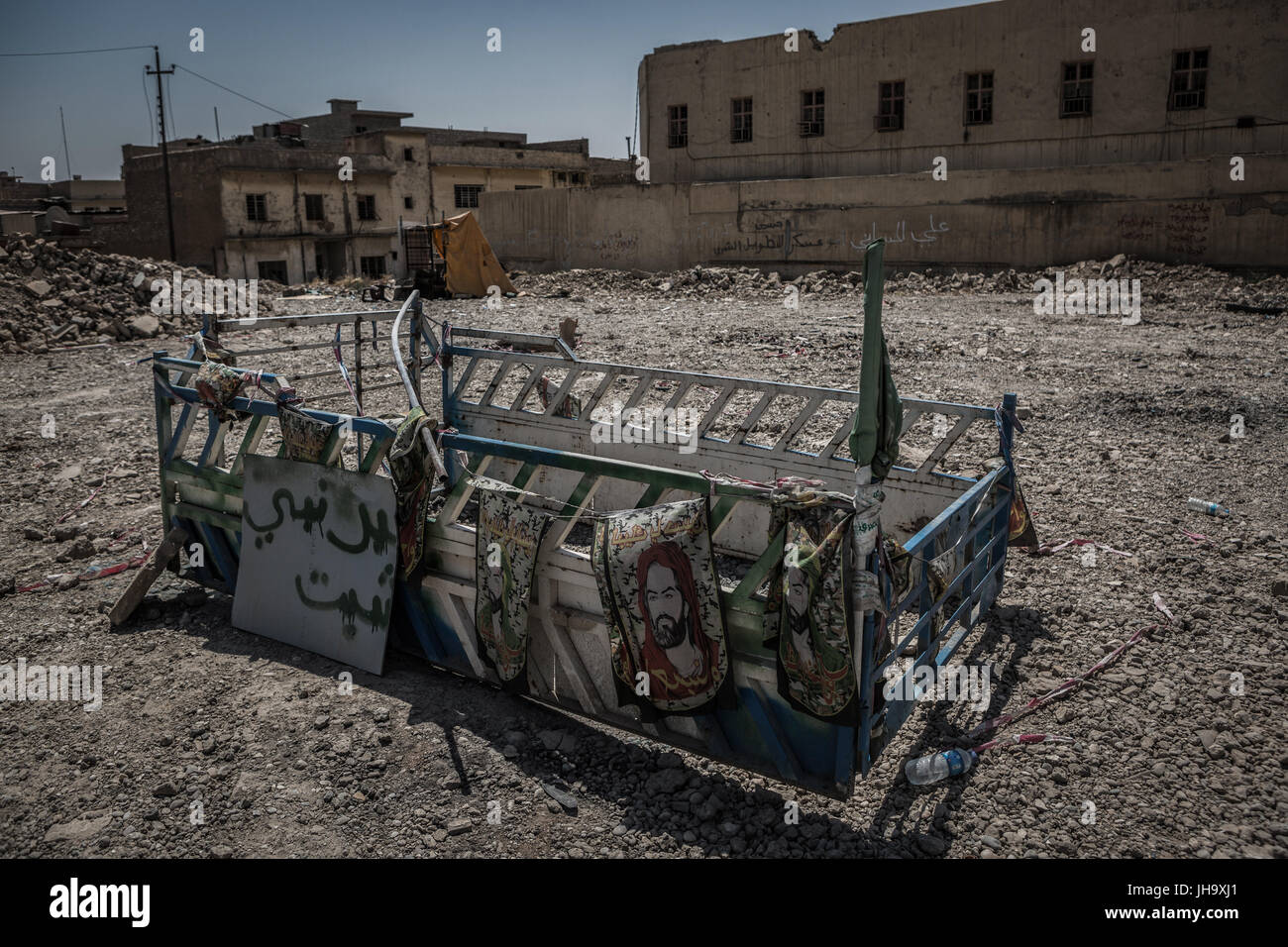 Mosul, Iraq. 12 Luglio, 2017. Realizzare localmente un santuario che ornano le bandiere raffiguranti Iman Ali, un simbolo importante per i musulmani sciiti in Iraq, si siede sul sito di una moschea distrutta a Mosul, Iraq, 12 luglio 2017. Il primo ministro iracheno Haider al-Abadi ha formalmente dichiarato la vittoria totale oltre lo stato islamico organizzazione terroristica a Mosul il 10 luglio 2017. Foto: Andrea Dicenzo/dpa/Alamy Live News Foto Stock