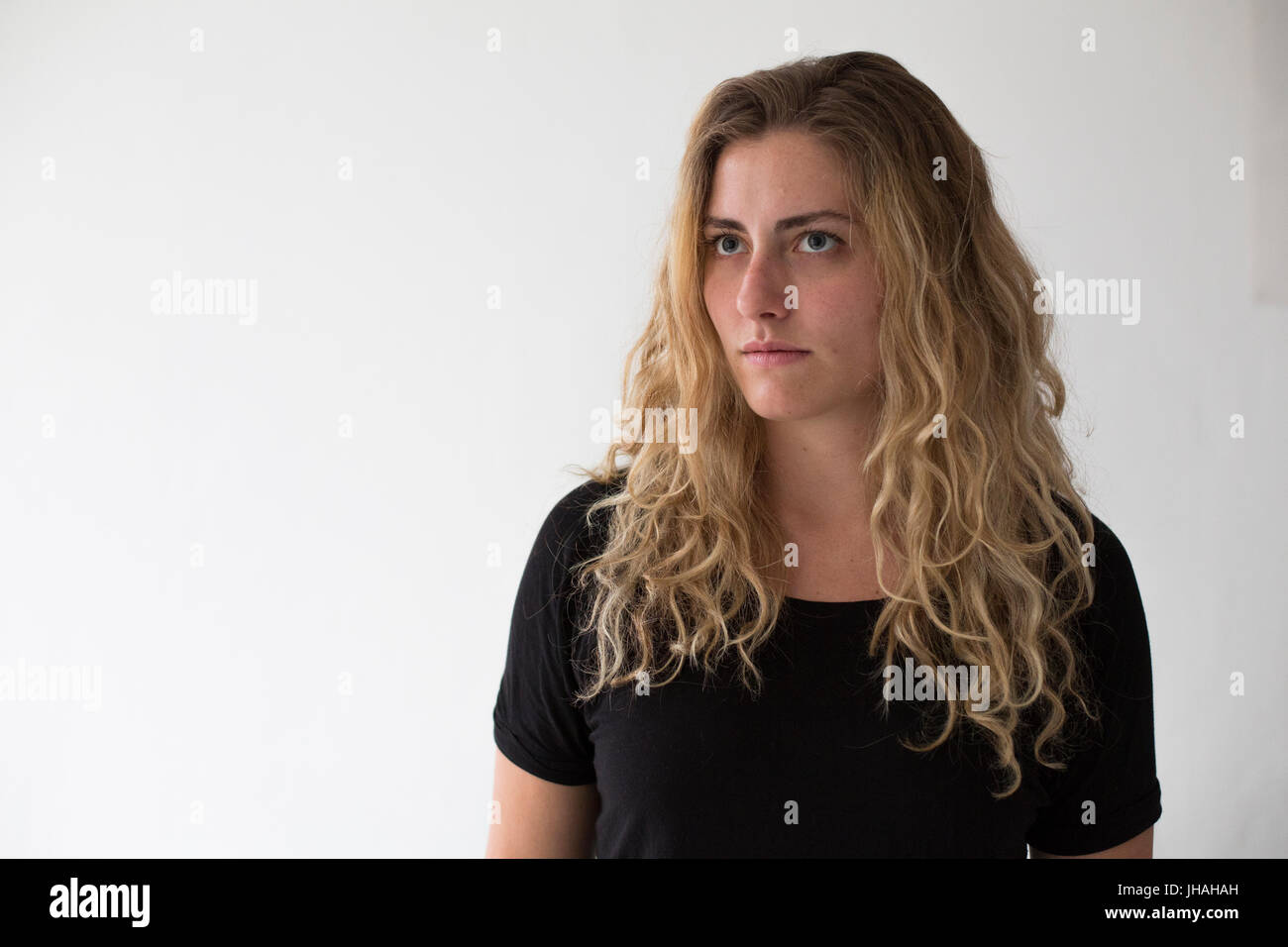 Giovani, bionda, donna caucasica esprime emozioni negative, ira, urlando e puntare il dito al visualizzatore e fotografo su uno sfondo bianco. Foto Stock