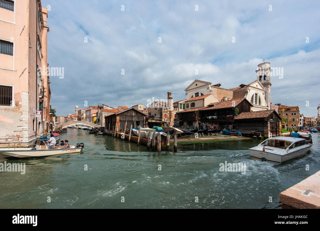 Immagini reali di Venezia: Barche a motore su un canale nel quartiere Dorsoduro con una gondola barca costruire e riparare il cantiere - workshop in background Foto Stock