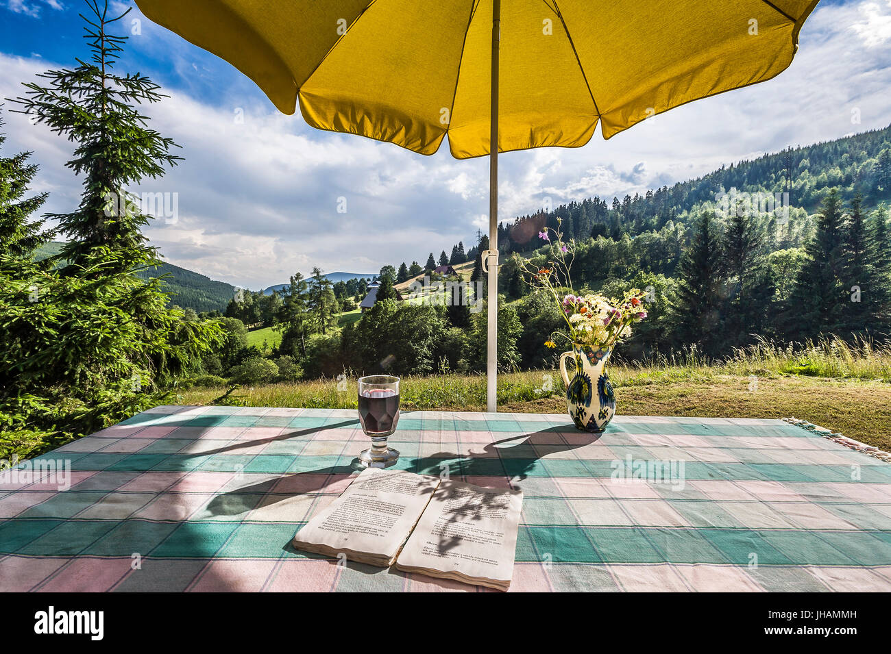 Tavolo con tovaglia e giallo ombrellino in montagna campagna estiva Foto Stock