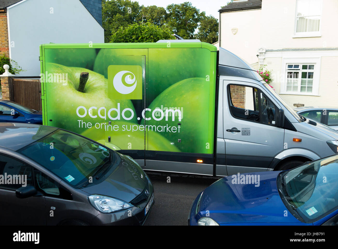 Ocado / Ocado.com supermercato / super mercato furgone in una strada residenziale o strada facendo home delivery & bloccando il flusso del traffico. Regno Unito Foto Stock