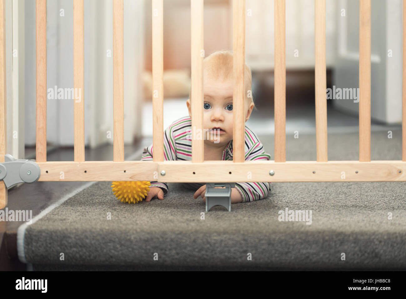 Il bambino gioca con la palla dietro cancelli di sicurezza Foto Stock