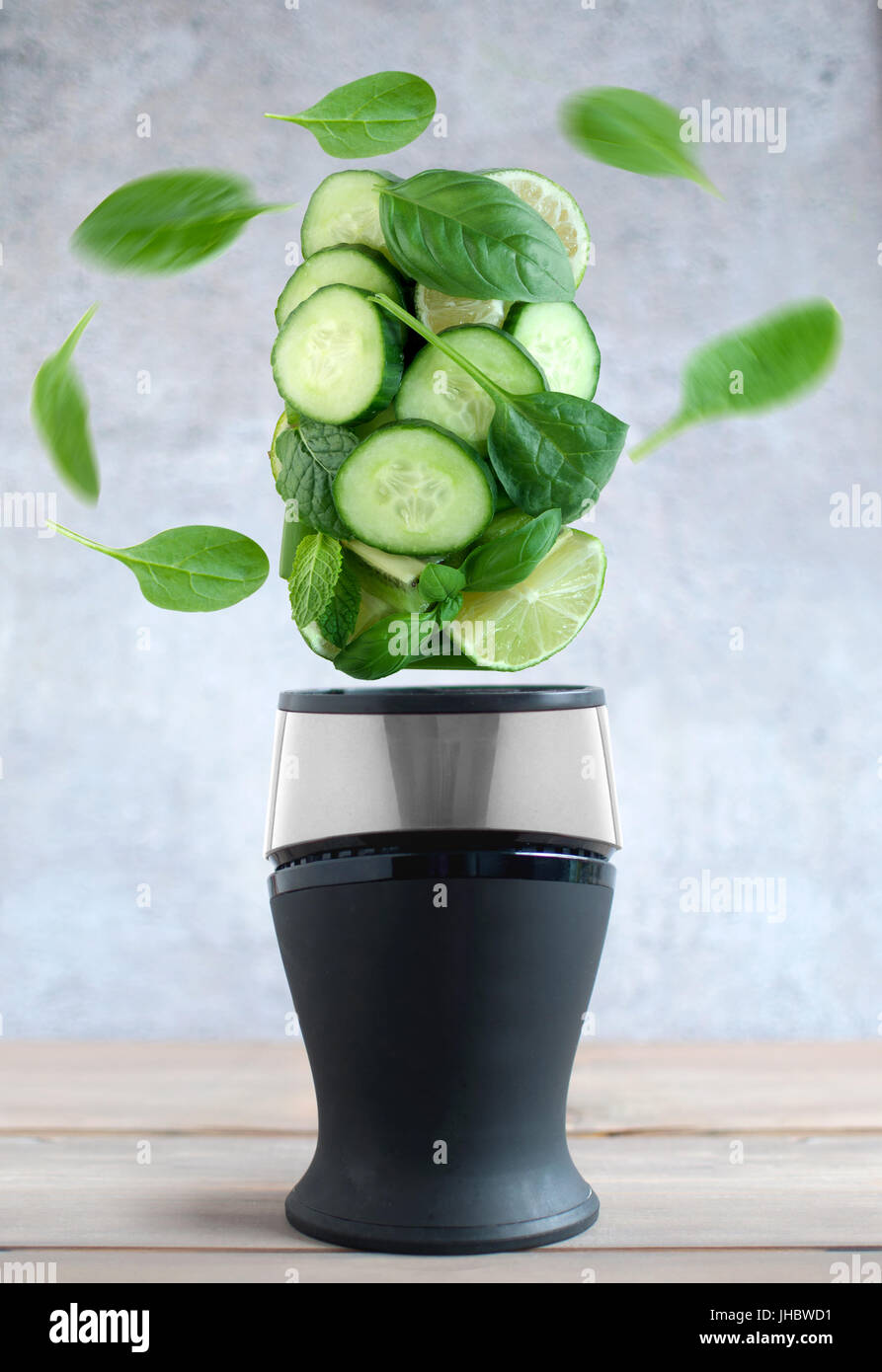 Verde fresco frutta e verdura la filatura intorno a un frullatore Foto Stock