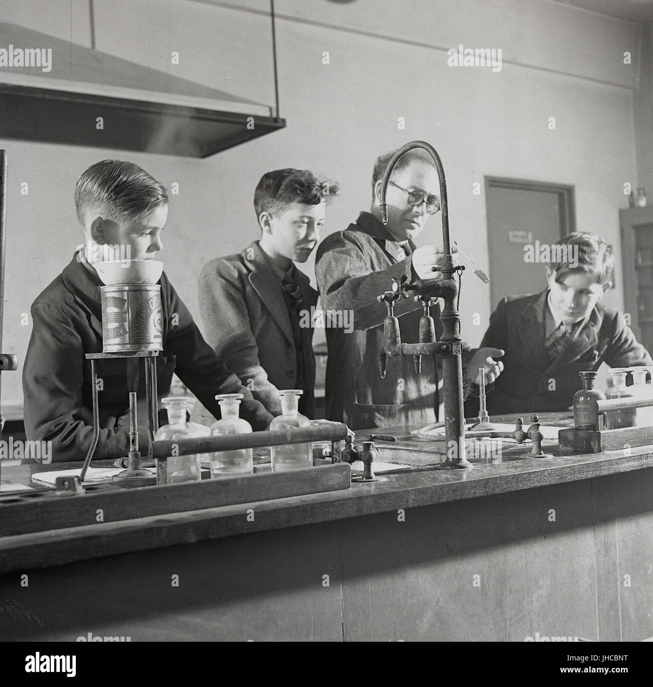 Degli anni Cinquanta, storico, Inghilterra, Regno Unito, nel laboratorio di scienze del sud-ovest dell' Essex Technical College - conoscere localmente come 'Popolare di università". La figura mostra un insegnante maschio utilizzando un testube per dimostrare come i diversi prodotti chimici reagiscono quando miscelati insieme. Foto Stock