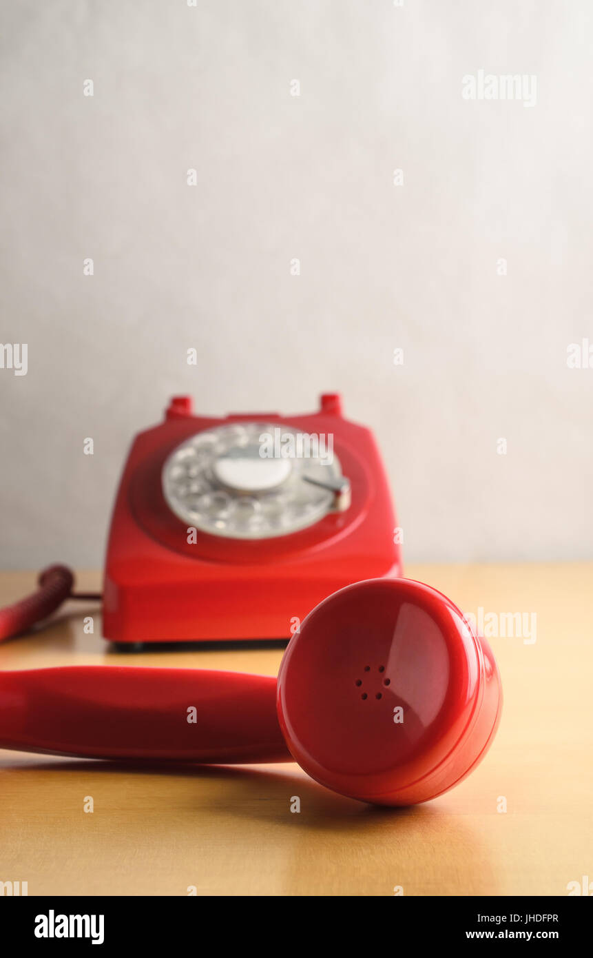 Il livello degli occhi colpo di un rosso retrò anni sessanta a 70s british style telefono, con ricevitore sganciato e in stretta fino in primo piano. Componi in base soft focus ba Foto Stock