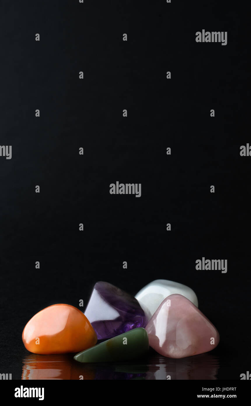 Una selezione di cristalli di quarzo sono raggruppate in una vita ancora la disposizione su sfondo nero, con riflettente, effetto di increspatura dell'acqua sottostante. Foto Stock