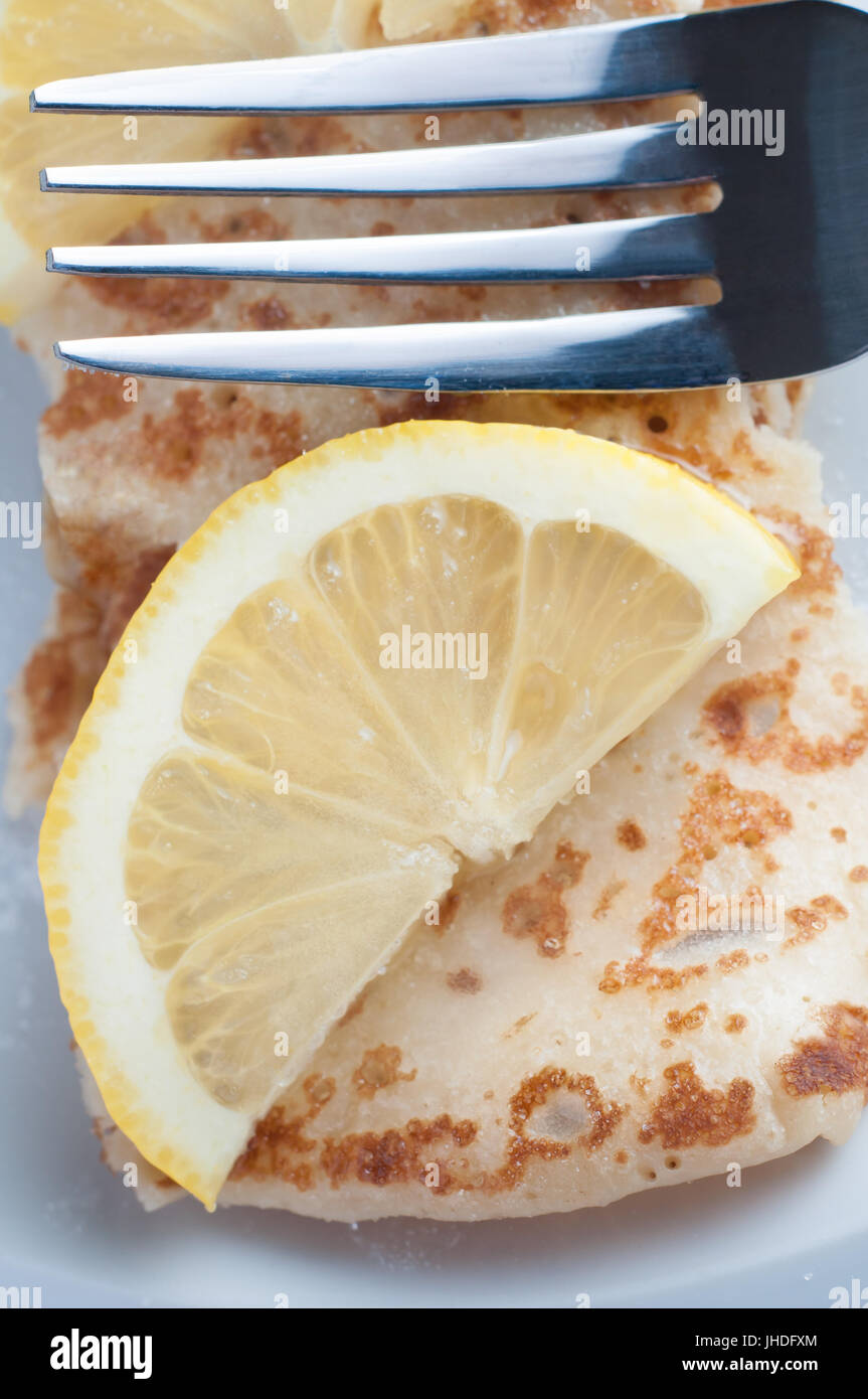 Close up shot di overhead di un tradizionale stile britannico pancake e rabboccato con fettina di limone e acciaio lucido forcella. Foto Stock