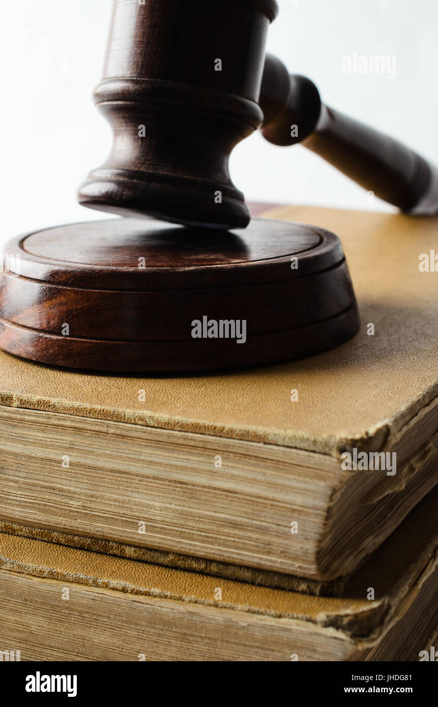 Vicino il concetto di legge colpo di vecchi libri impilati e guarnita con martello di legno su sfondo bianco. Foto Stock
