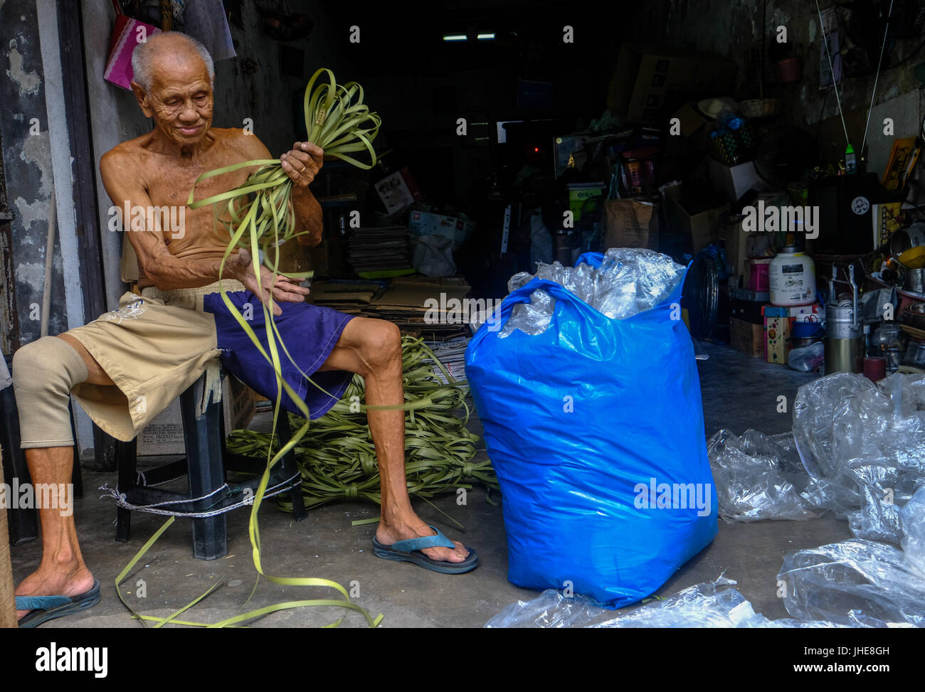 Un anziano uomo cinese lavora al di fuori della sua posizione di affari in Georgetown, Penang, Malaysia Foto Stock