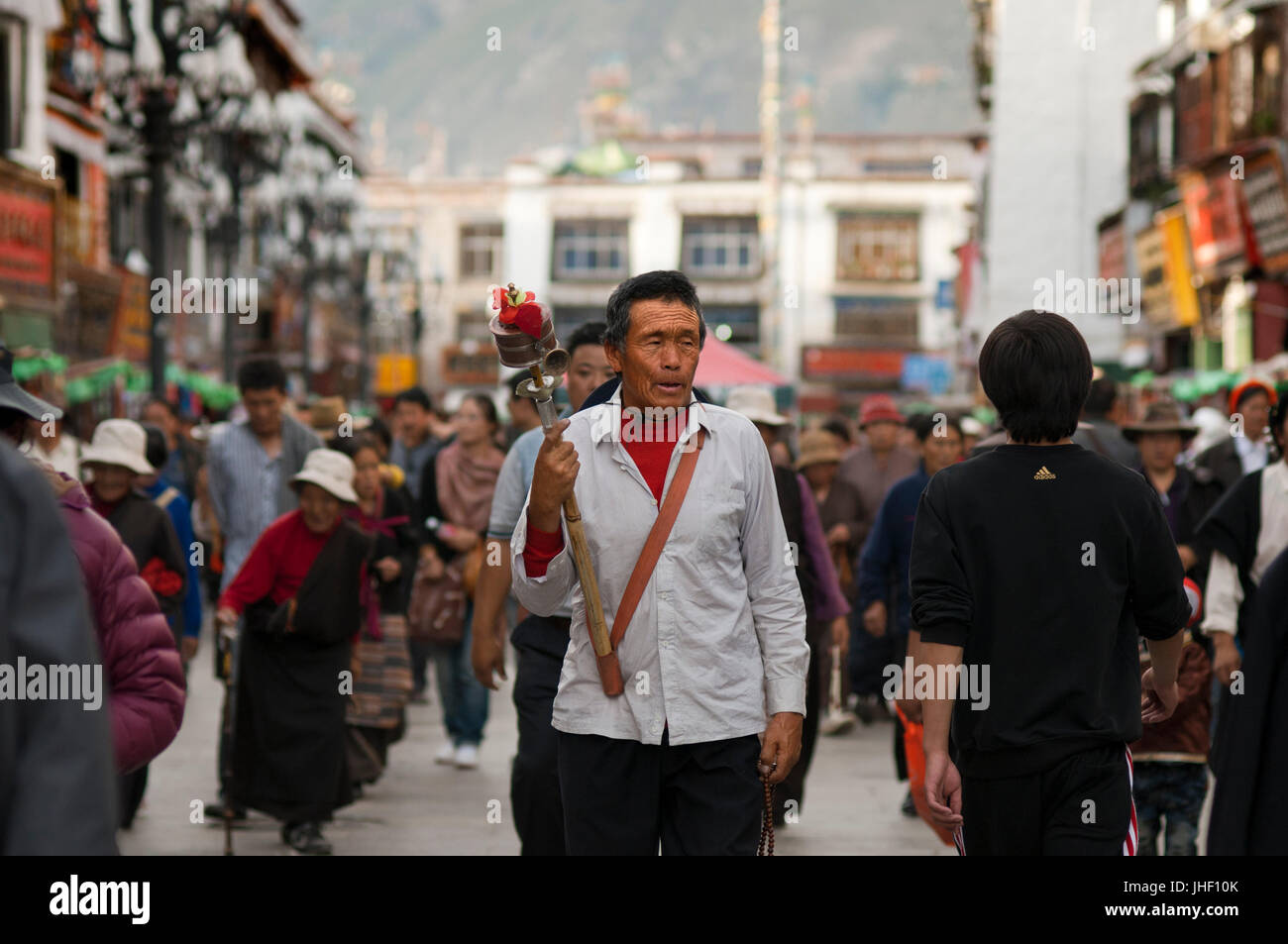 Buddista Tibetana devoti fare la Kora in senso orario circumambulation intorno al tempio di Jokhang, Lhasa il Tibet. Pellegrino con una ruota di preghiera Foto Stock