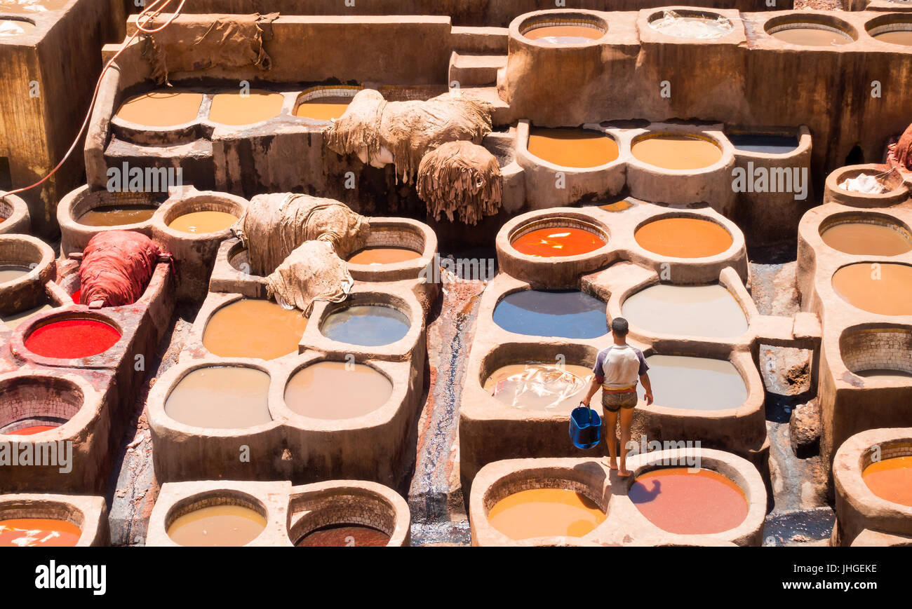 Fez, in Marocco - Maggio 07, 2017: giovane uomo non identificabili con una benna in piedi su delle vasche di una pelle di conceria guardando le pelli che stabilisce nel colorante. Foto Stock