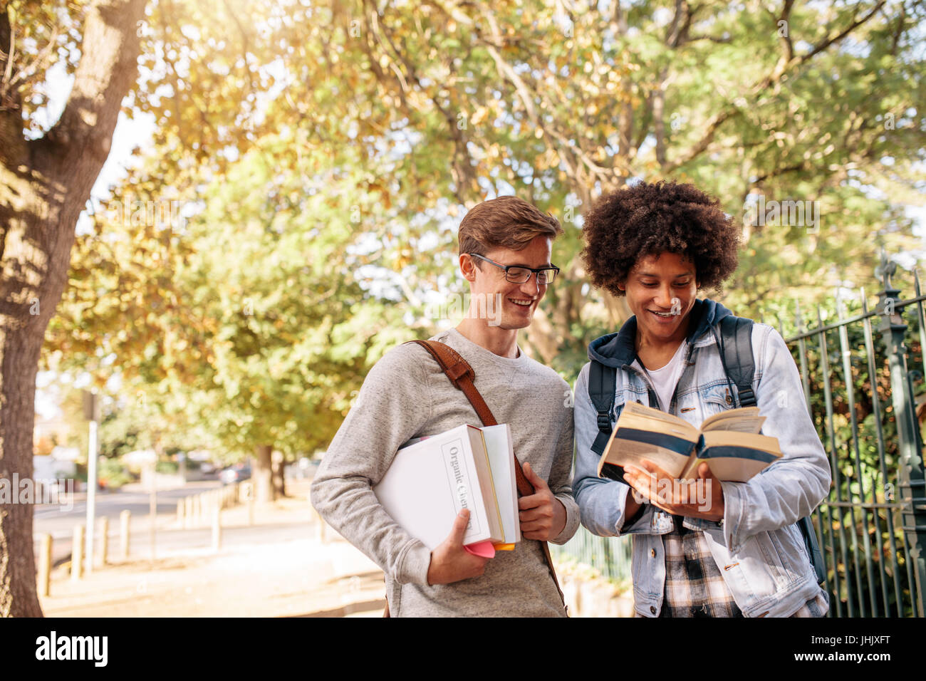 Studenti universitari libro di lettura nel campus universitario. I giovani studenti del college con libri sulla strada. Foto Stock