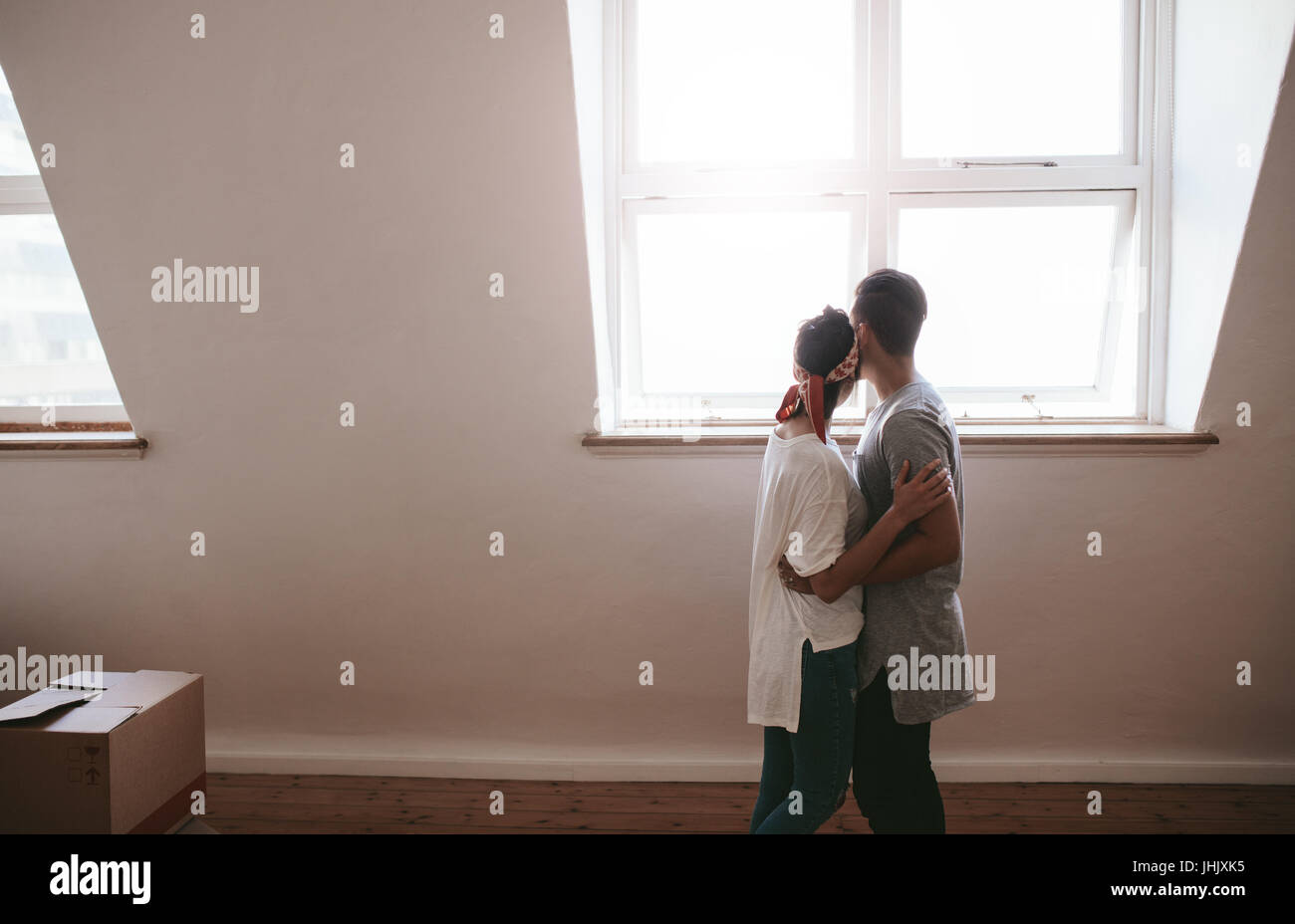 Amorevole coppia giovane muovendo in un nuovo appartamento. L uomo e la donna in piedi insieme con scatole sul pavimento. Foto Stock