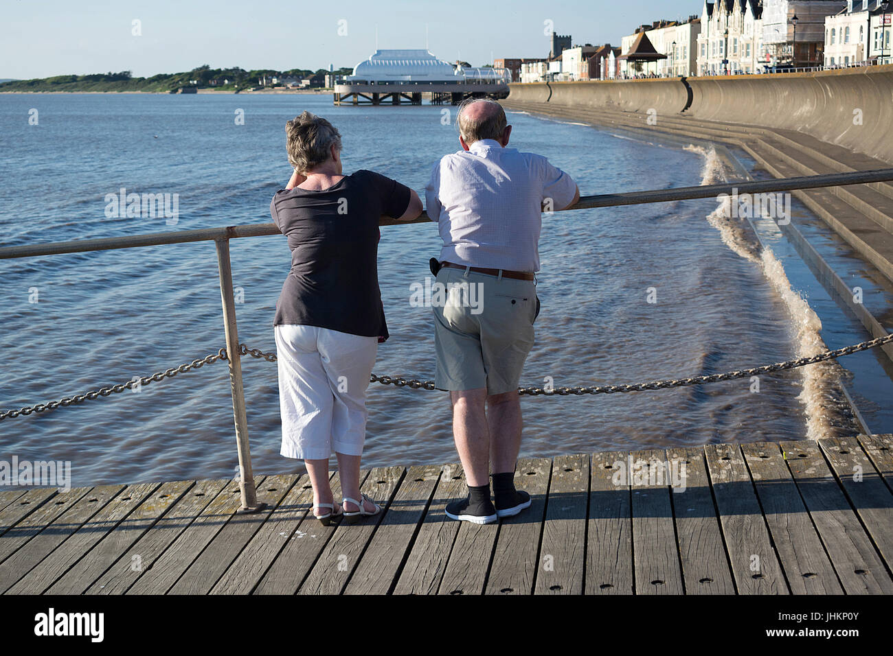 Coppia di anziani al mare in piedi che guarda al mare e il molo di una cittadina britannica Foto Stock
