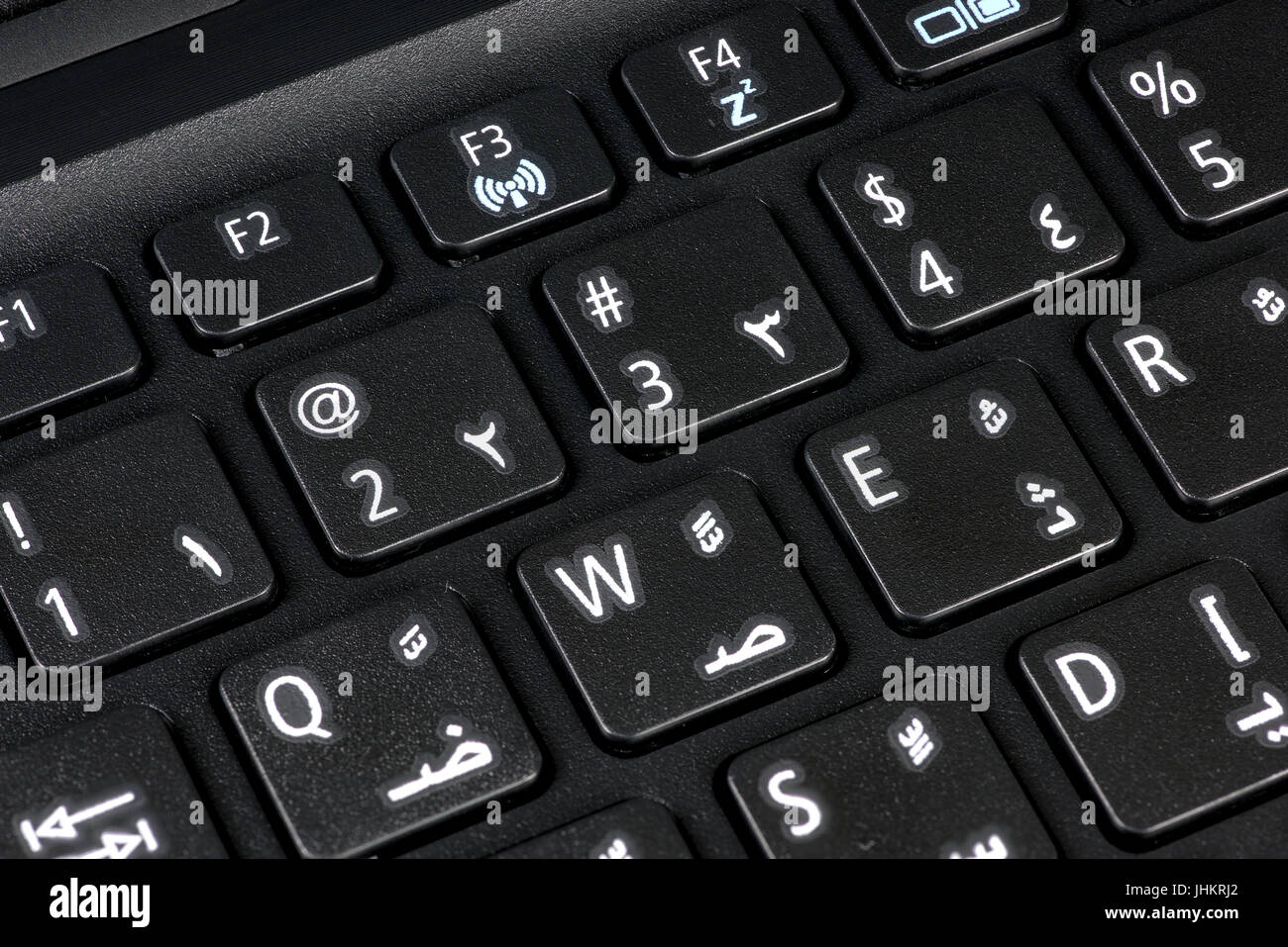 Primo piano di una tastiera QWERTY con lettere inglesi e arabe, con figure visibili, che illustrano la comunicazione bilingue e multiculturale Foto Stock