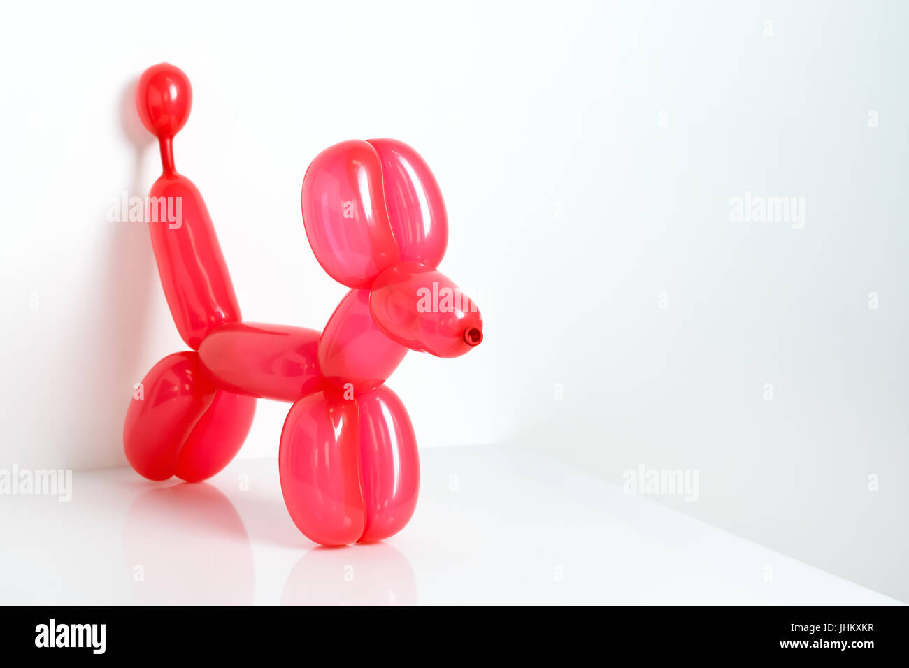 Red semplice twisted palloncino cane animale su bianco. Giocattolo di palloncini, spazio libero per il testo. Palloncino art. Foto Stock