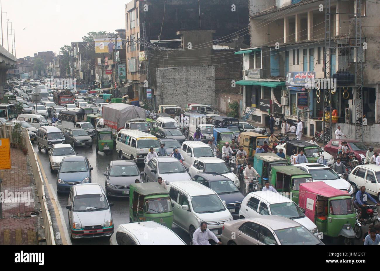 Pendolari passando attraverso la pioggia a Lahore venerdì 14 luglio, 2017. L'acquazzone torrenziale a Lahore inondato le aree pianeggianti di Lahore. Foto Stock