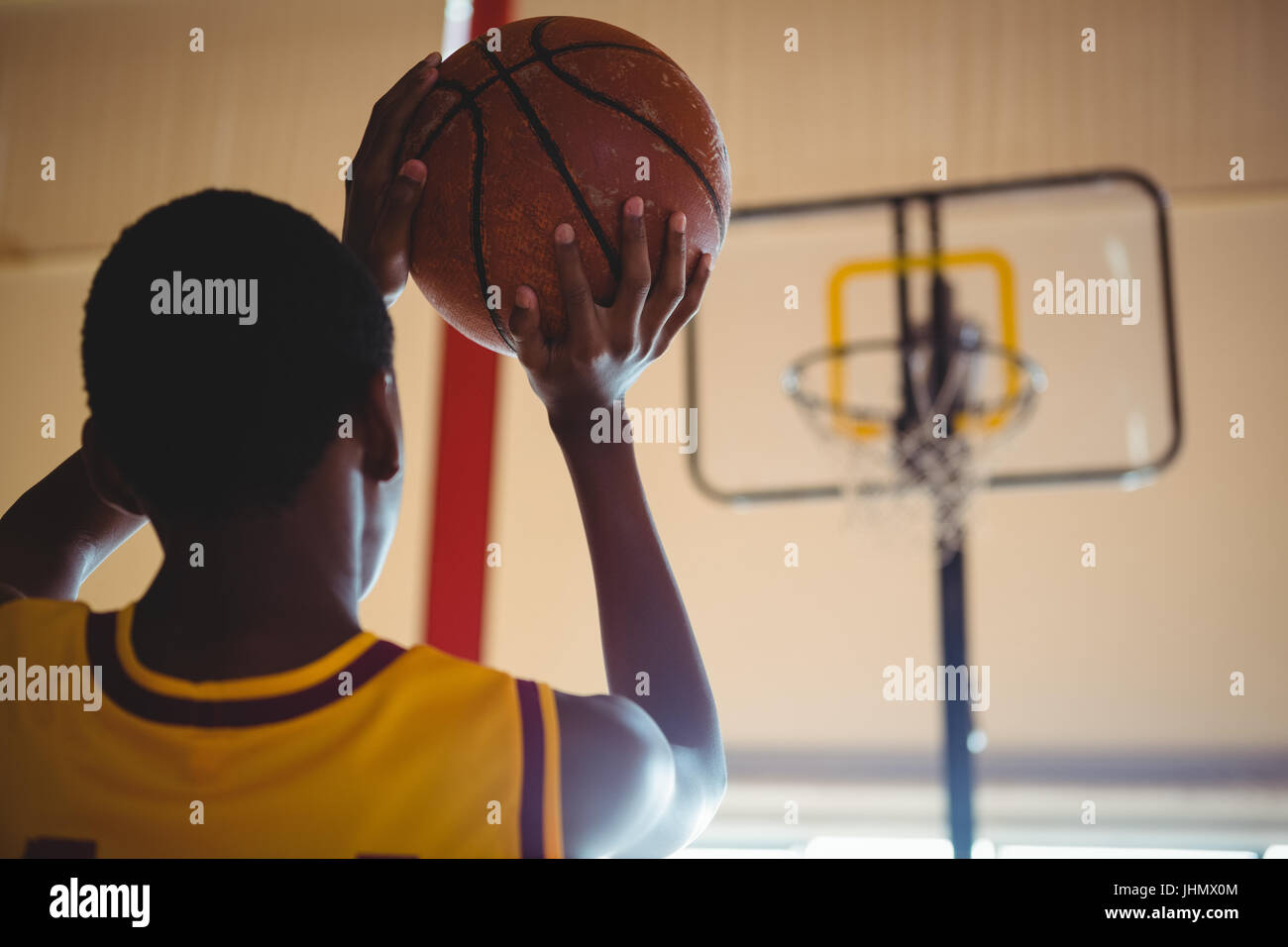 Vista posteriore del ragazzo adolescente giocando a basket in tribunale Foto Stock