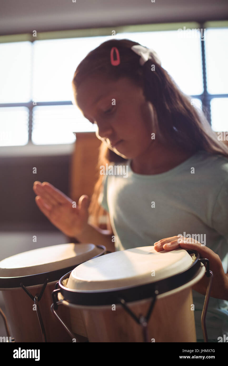 Ragazza praticando i tamburi di bongo in aula presso una scuola di musica Foto Stock