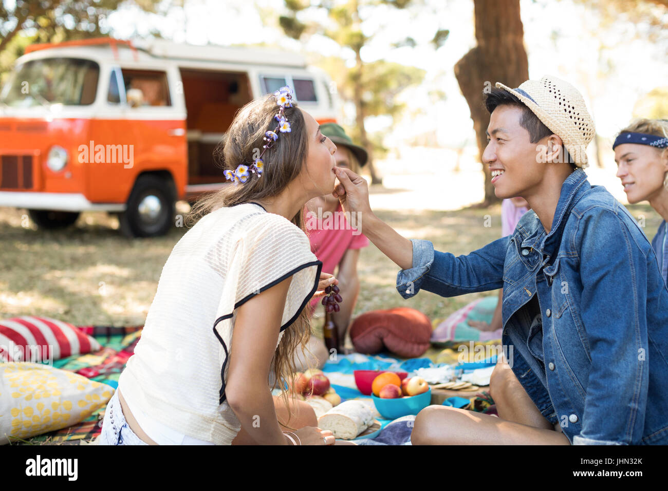 Mman frutto di alimentazione ad un amico durante la seduta sul campo durante il picnic Foto Stock