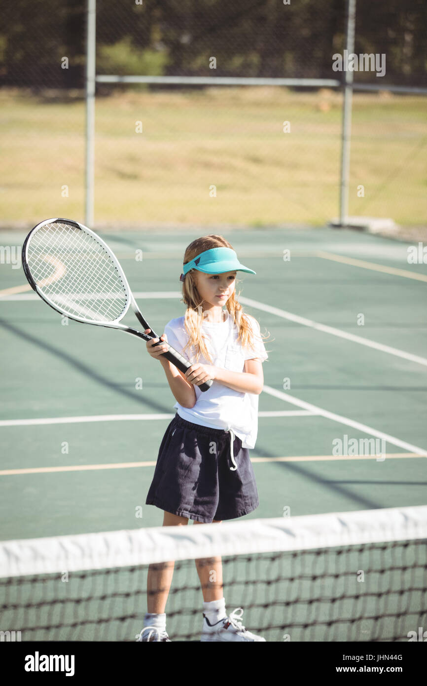 Ragazza giocando a tennis presso la corte durante la giornata di sole Foto Stock