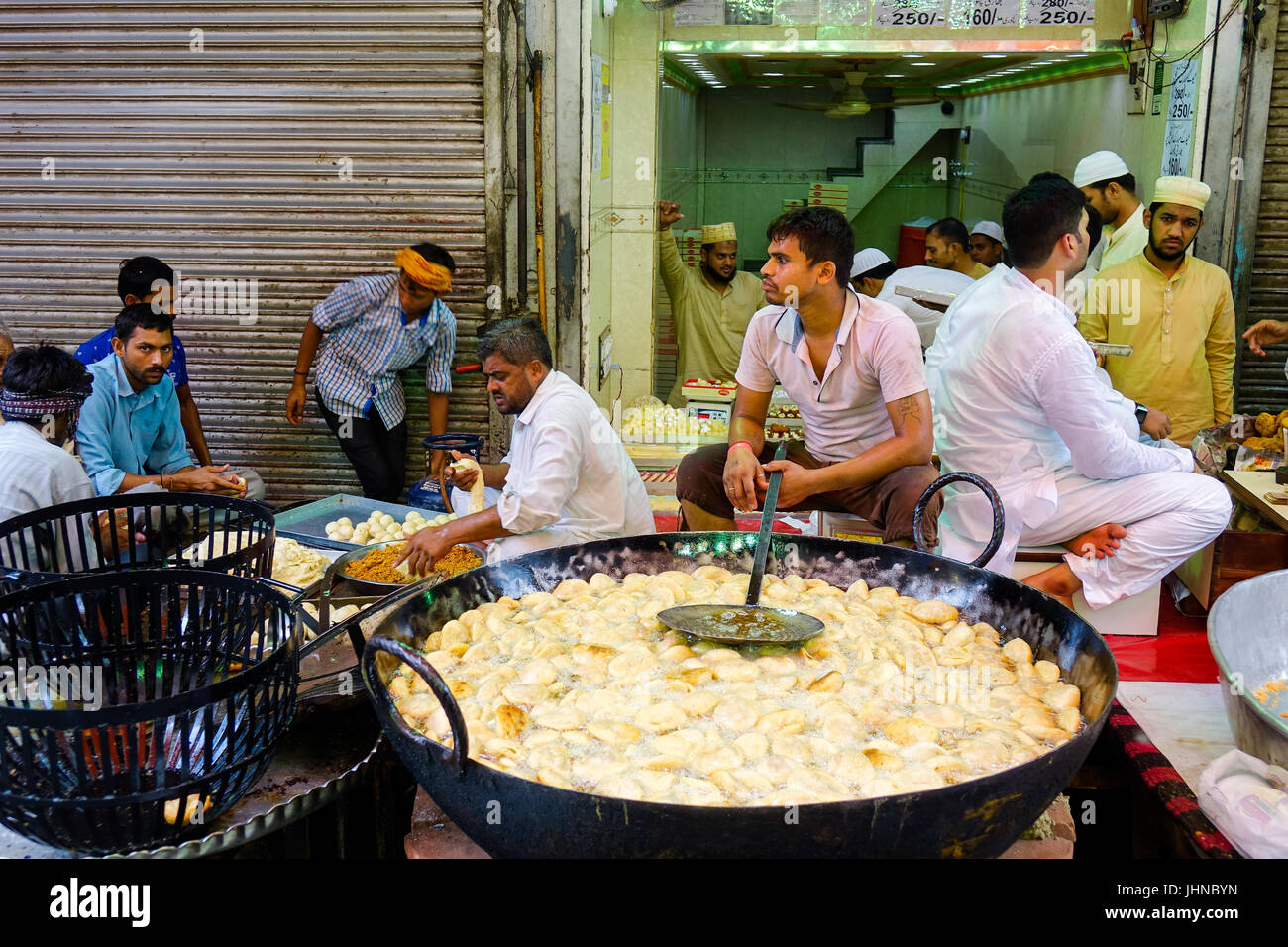 Uomo kachori frittura in tondo grande padella ovvero Karahi, per la festa musulmana di Eid al-fitr, gli acquirenti in attesa di essere preparato Foto Stock
